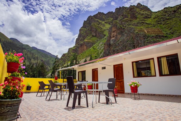 A terrace with outdoor seating and potted plants, overlooking a mountainous landscape.