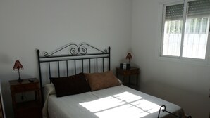 Une chambre à coucher comprenant un lit, une table de chevet, une commode, une fenêtre et une chaise.