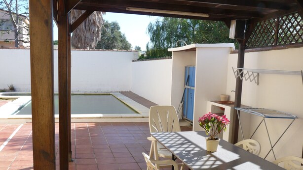 Une terrasse avec une table et des chaises, une petite piscine et une plante en pot.