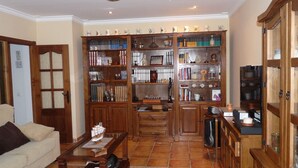 Un salon avec une bibliothèque en bois, un téléviseur et une table basse.