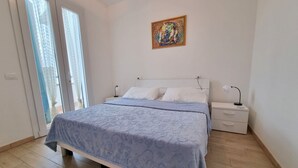 Une chambre à coucher avec un lit, des tables de chevet, un tableau et une porte-fenêtre coulissante.