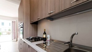 Une cuisine moderne avec des meubles en bois, une cuisinière à gaz, une bouteille de vin et un évier.