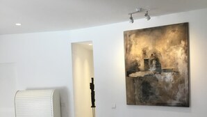 A minimalist room with a large abstract painting, a white radiator, and a hallway leading to another room. - Lovely Andalucian villa in a quiet, green neighborhood (Estepona)