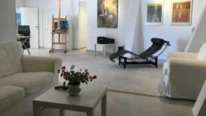 A modern living room with a reclining chair, a sofa, a coffee table with a flower arrangement, and artwork on the walls. - Lovely Andalucian villa in a quiet, green neighborhood (Estepona)