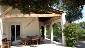 An outdoor patio with wooden furniture, a pergola, and a view of the surrounding greenery. - house - 4 rooms - 4/6 persons (Conqueyrac)