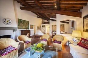 A spacious living room with wicker furniture, a fireplace, and a staircase leading to an upper level.