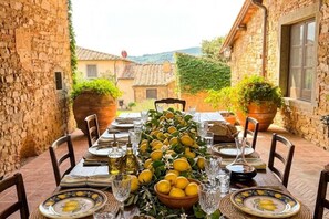 Mesa lista para comer con vista a un edificio de piedra y follaje.