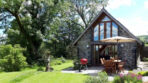Una casa de piedra con un patio, una parrilla y mobiliario para exteriores.