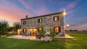 A stone house with a patio, outdoor seating, and a view of the countryside at dusk. - Country House Casale dei Gelsi Entire property including swimming pool for private use (Castiglione in Teverina)
