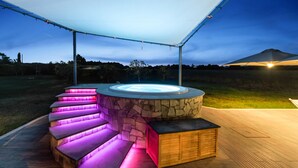 A circular outdoor hot tub with a stone wall and wooden seating, surrounded by a covered patio area. - Country House Casale dei Gelsi Entire property including swimming pool for private use (Castiglione in Teverina)