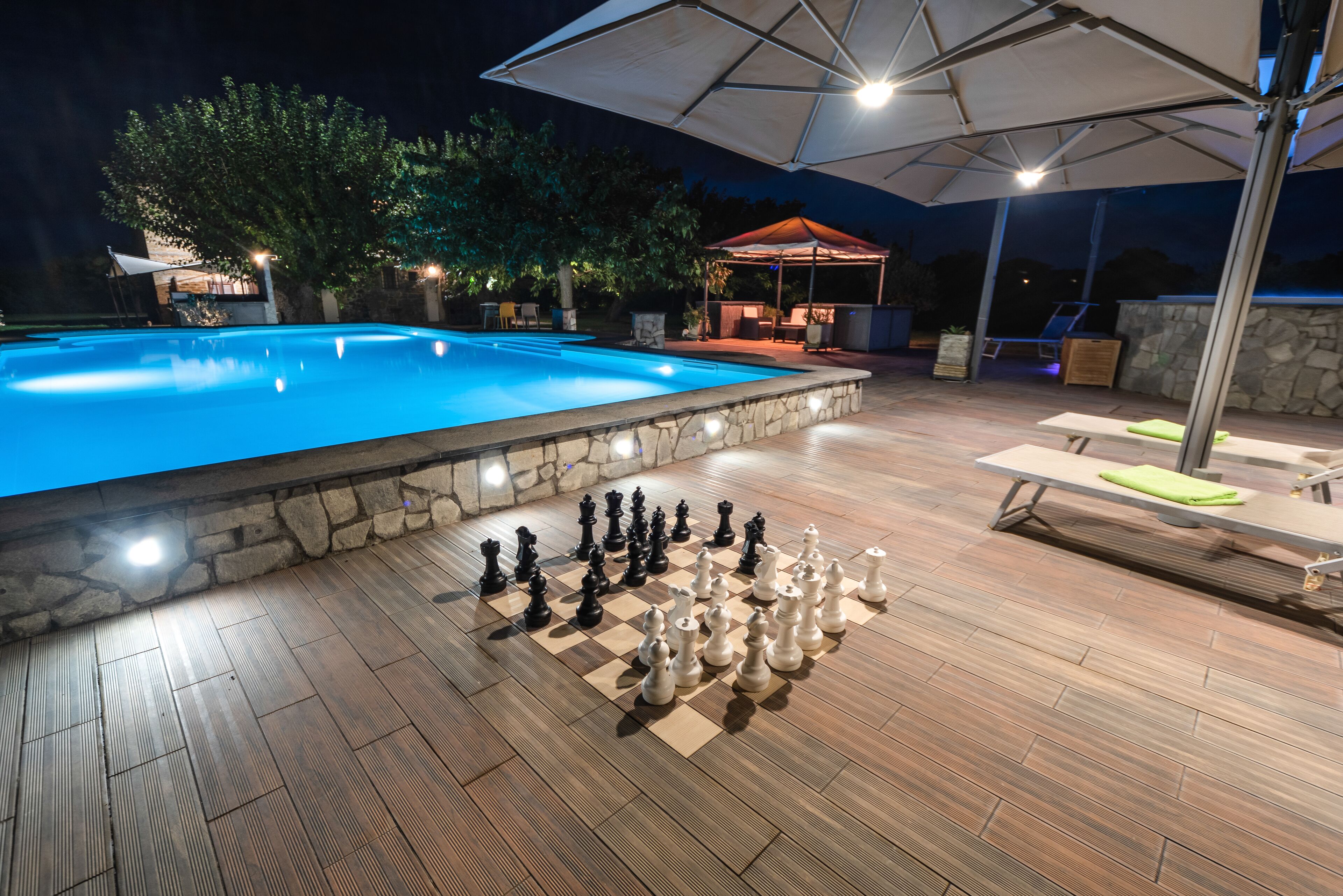 An outdoor pool area with a chessboard set up for a game.