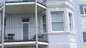 Un edifici de diverses plantes amb un balcó al segon pis, una porta negra i façana blanca.