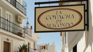 Een smalle straat met een bordje voor hotel 'La Covacha de Macondo'.