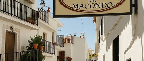 Une rue étroite avec une enseigne indiquant l’hôtel « La Covacha de Macondo ».
