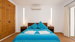 Een slaapkamer met een bed, twee nachtkastjes, een kledingkast en een raam met gordijnen.