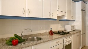 A kitchen with white cabinets, a granite countertop, a sink, a microwave, and a stove. - Lovely 2 bedroom apartment with air con and excellent communal pool & bar (Fonte Santa)