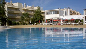 A clear swimming pool with lounge chairs and umbrellas, a building with multiple balconies, and a clear sky. - Lovely 2 bedroom apartment with air con and excellent communal pool & bar (Fonte Santa)