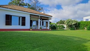 Una casa moderna con techo de tejas, un porche cubierto y un césped bien cuidado.