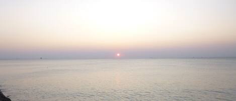 Mar tranquila al atardecer con un litoral rocoso en primer plano.