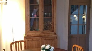 A dining area with a wooden table, chairs, a cabinet with glass doors, and a door with a window. - Character house surrounded by vineyards 6 pers (Bollène)