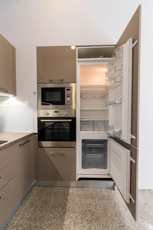 Een praktische keuken met een inbouwmagnetron, oven en koelkast, met een minimalistisch ontwerp en veel opbergruimte.