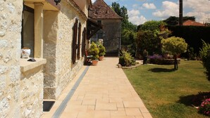 A stone building with a tiled roof, a paved pathway, and potted plants. - "Les Mirabelles"  in deep rural France - (Gardonne)