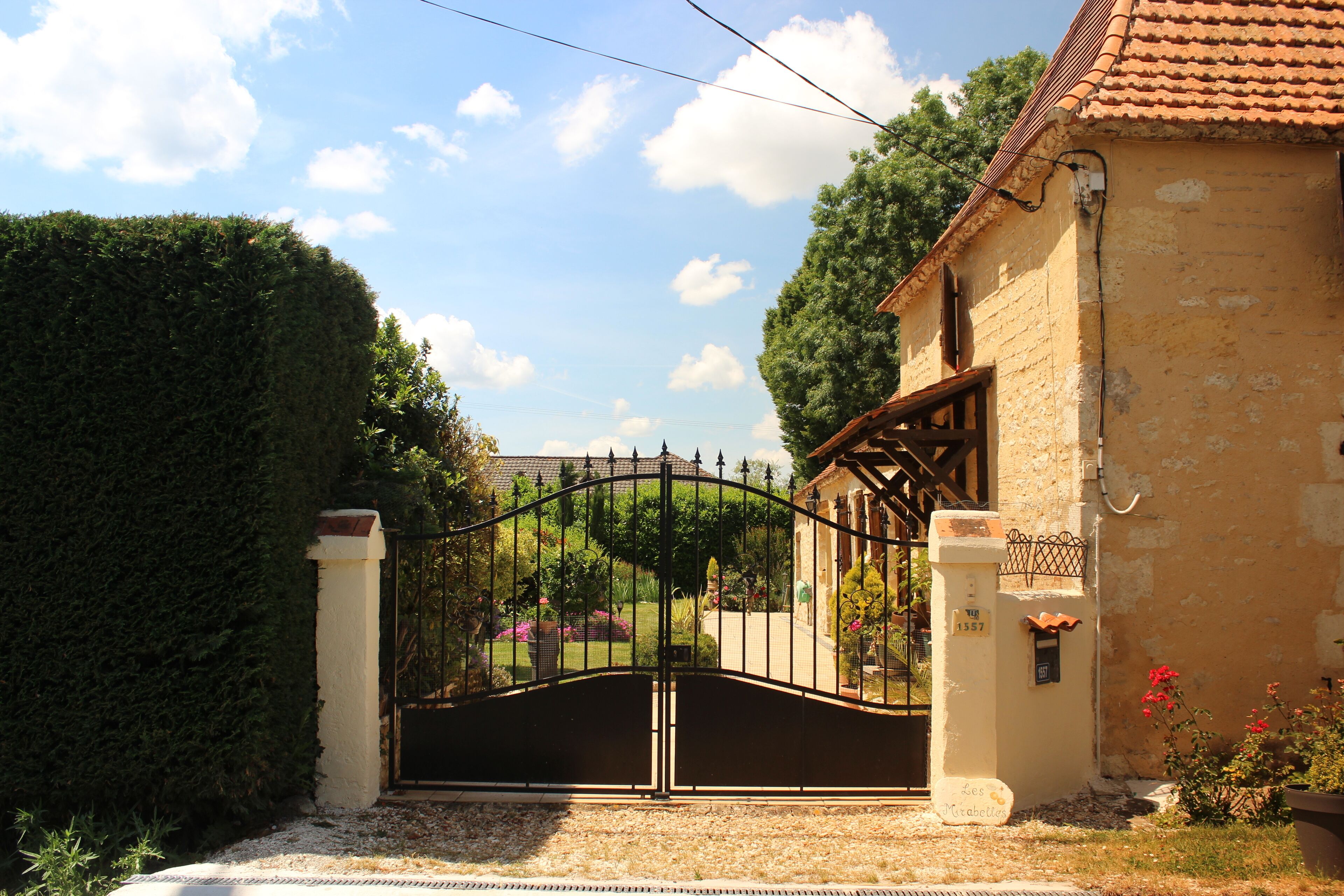 A gated entrance to a property with a stone wall and a tiled roof.