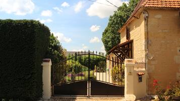 A gated entrance to a property with a stone wall and a tiled roof.