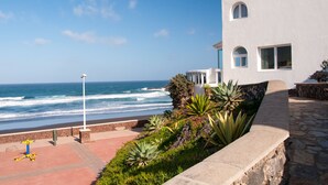 Un edificio costero con un sendero de piedra que conduce a la playa, con vista al océano.