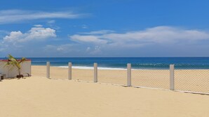 Une plage avec une clôture, un banc et un petit bâtiment doté d’un toit rouge.