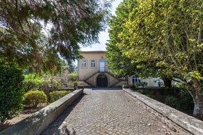 A cobblestone pathway leading to a building with a tiled roof and a central entrance. - Cottage with pool near the beach (Neiva)
