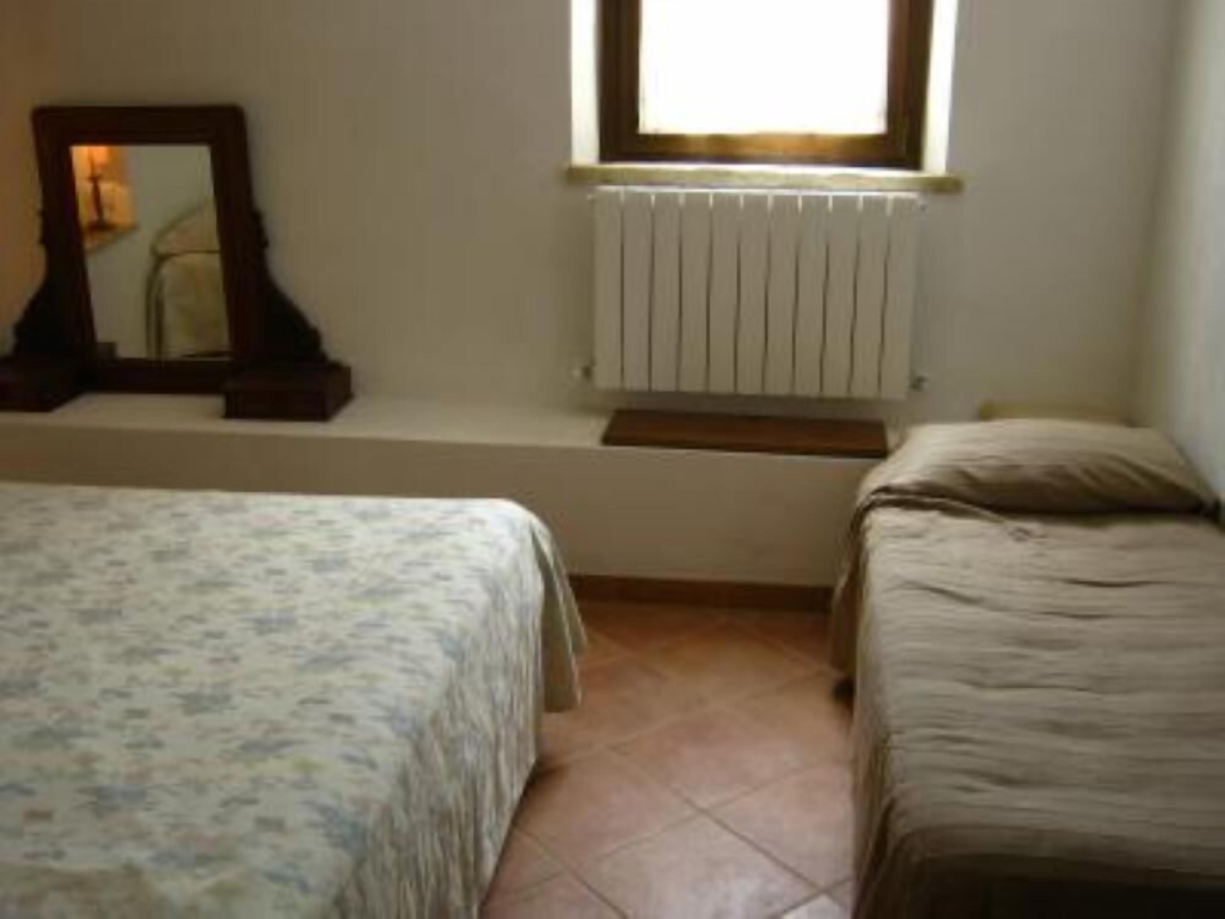 Une chambre avec deux lits simples, un radiateur, une fenêtre et un miroir au mur.