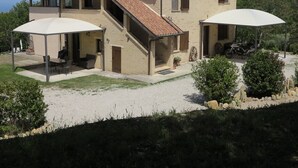 Ein zweistöckiges Haus mit einer Terrasse, Sitzgelegenheiten im Freien und Blick auf die umliegende Landschaft.