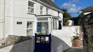 A white two-story house with a blue gate, a chimney, and a sign reading "ELMAR".