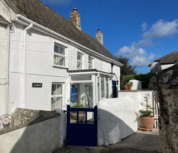 A white building with a blue gate, a chimney, and a sign reading 'ELMAR'.