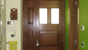 Un pasillo con una puerta de madera, un radiador y una pared verde.