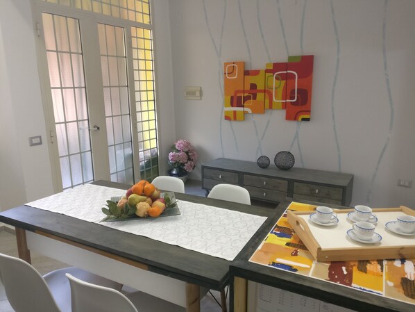 A dining area with a table set for four, a vase of flowers, and a decorative wall piece.