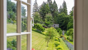 A view of a lush garden with a stone wall, a tree, and various shrubs.