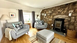 A living room with a stone wall, a fireplace, a sofa, a chair, and a rug.