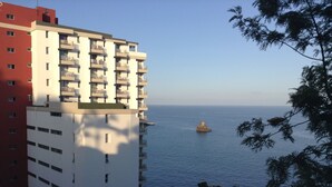 A high-rise building with multiple balconies overlooking a calm sea. - Bright Seafront Apartment In Funchal with Sea View from the Balcony (Funchal)