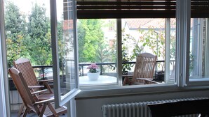 A balcony with two wooden chairs and a potted plant.