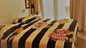 Ein Schlafzimmer mit Bett, Nachttisch, Lampe und einem Fenster mit Vorhängen.