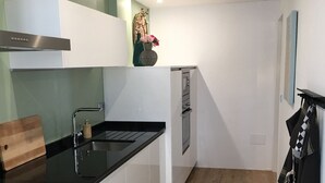 Eine moderne Küche mit weißen Schränken, einer schwarzen Arbeitsplatte und Holzboden.