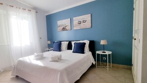 Ein Schlafzimmer mit einem großen Bett, zwei Wandleuchten und zwei gerahmten Bildern.