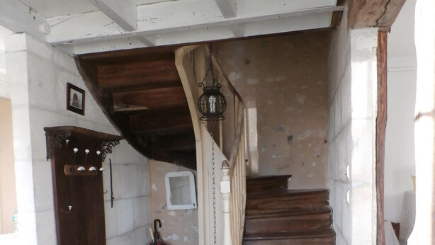 A wooden staircase with a white balustrade, a hanging lantern, and a small window.
