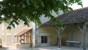 Un edificio con una veranda coperta, un muro in pietra e un tetto in tegole.