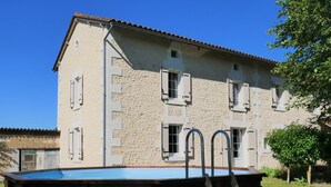 Un edificio di due piani con piscina, un pontile in legno e una scala che conduce alla piscina.