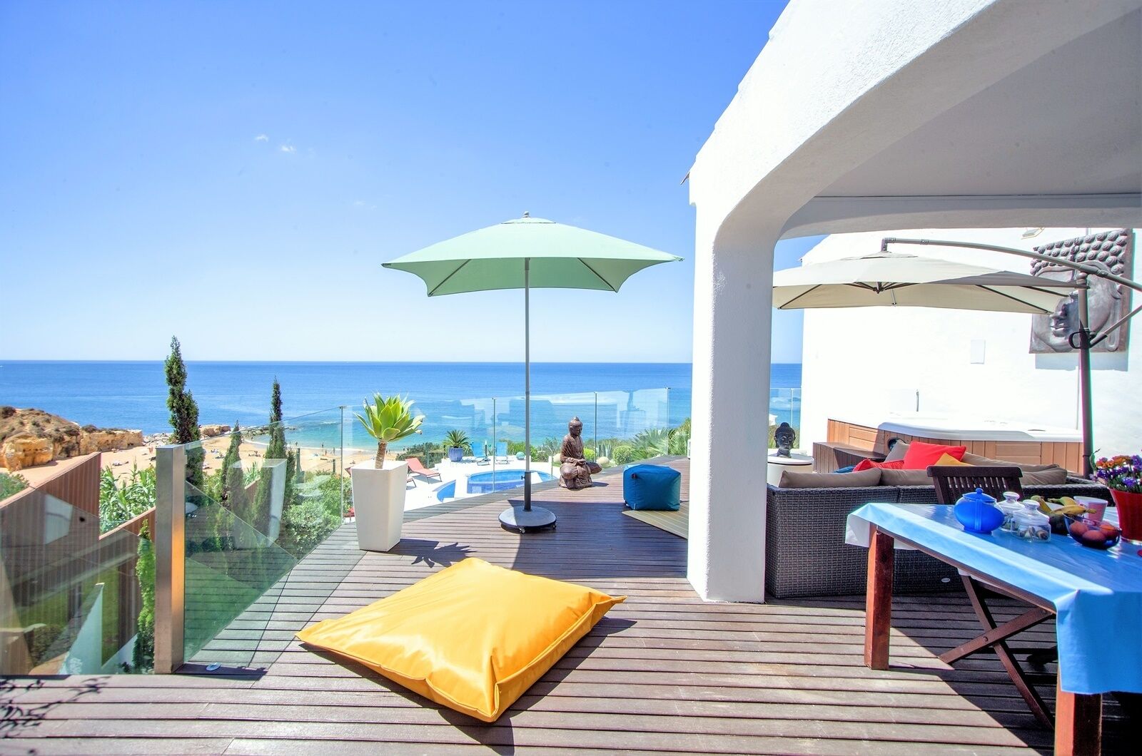 A wooden deck with a pool, outdoor seating, and a view of the sea.