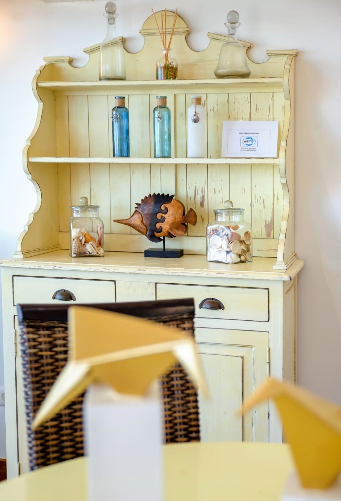 A vintage-style wooden cabinet with glass jars and a decorative fish sculpture.