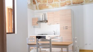 A kitchen with a stone ceiling, white cabinets, a wooden dining table, and a chandelier.